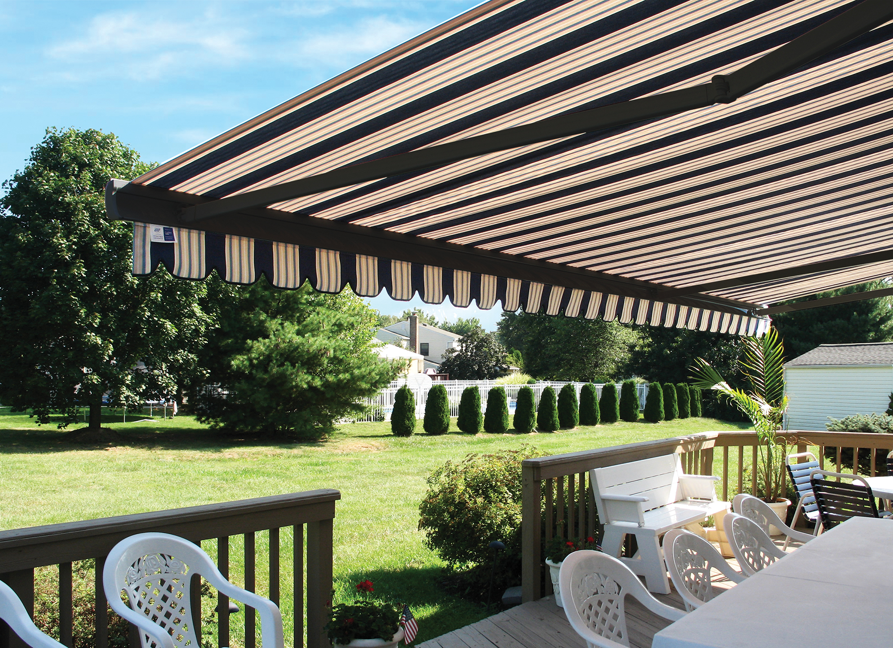 Motorized retractable awning extending over outdoor deck with patio furniture
