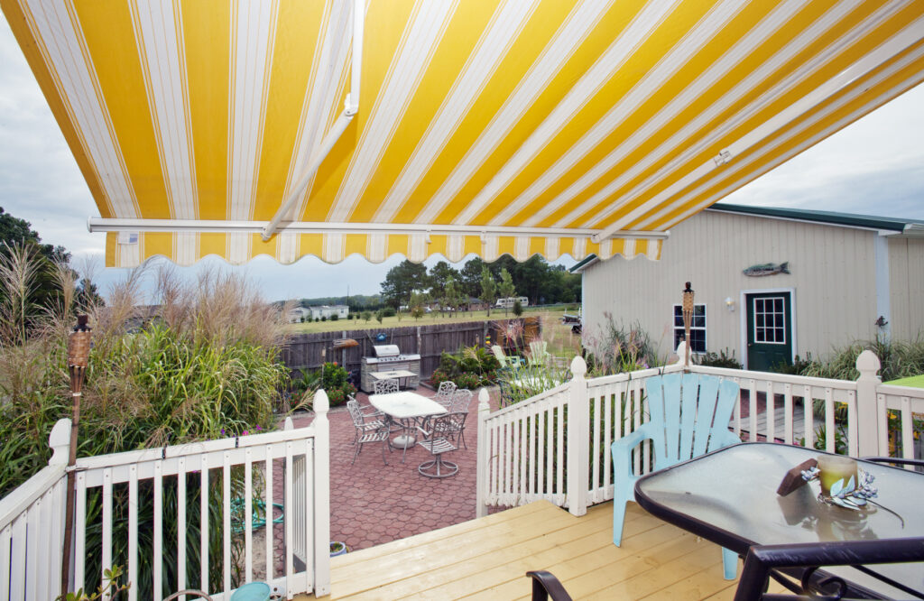 Patio with yellow striped awning and outdoor seating.